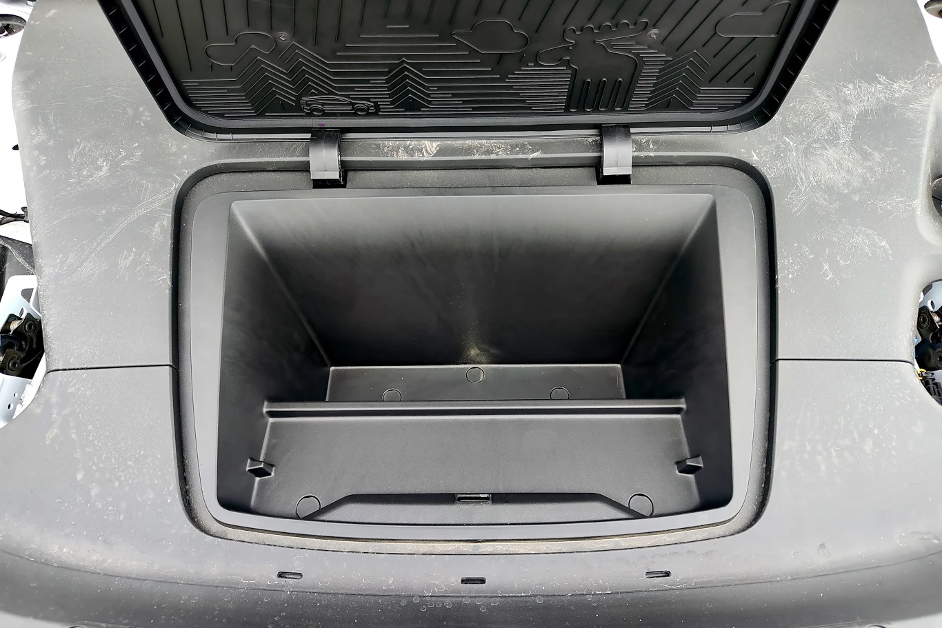 Frunk, czyli schowek pod maską Volvo EX30 ma tylko 7 litrów Otwarty bagażnik przedni samochodu elektrycznego z wyraźnie widoczną dużą, pustą przestrzenią oraz plastikową osłoną umożliwiającą łatwe przechowywanie przedmiotów.