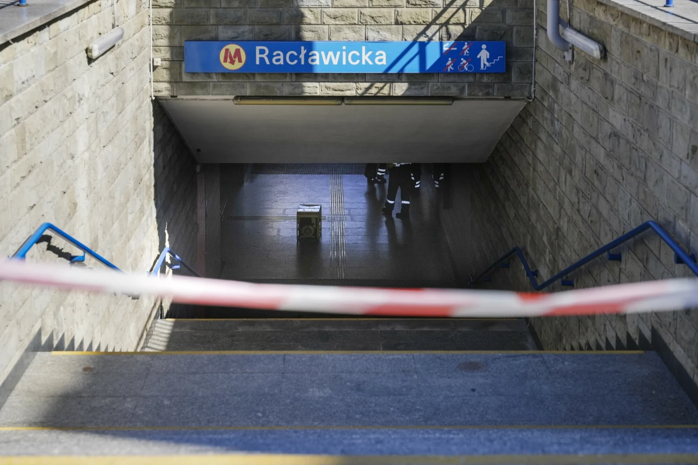 Stacja M1 "Racławicka" znów działa. Najnowszy komunikat Zamknięte wejście do stacji metra Racławicka, zabezpieczone taśmą ostrzegawczą, z pustymi schodami prowadzącymi do podziemia, na którym widoczne są odbicia światła na podłodze.