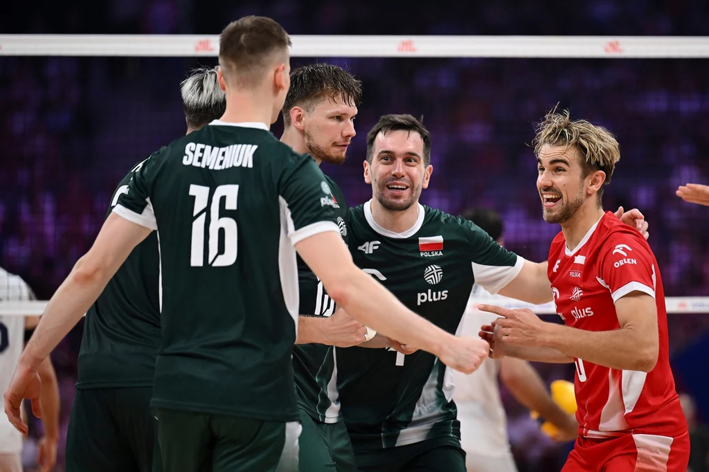 Mecz Iran - Polska w Lidze Narodów Grupa siatkarzy w zielonych i czerwonych strojach w dynamicznej sytuacji podczas meczu, zawodnicy wyrażają radość po zdobyciu punktu, w tle widać siatkę i rozmazaną widownię.