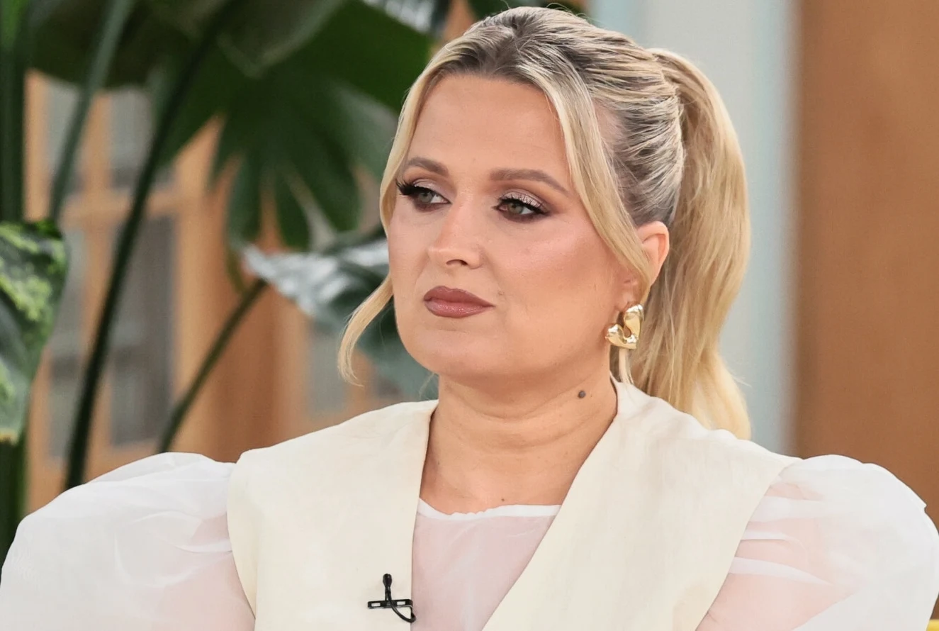 Gosia Andrzejewicz mówi o tym, co składa się na wzrost cen koncertów Kobieta o blond włosach spiętych w kucyk, ubrana w elegancki, jasny strój, siedzi w pomieszczeniu, w tle widoczne zielone liście dużej rośliny.