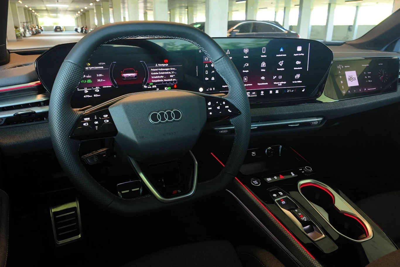 Audi A6 z napędami spalinowymi nie różni się wewnątrz od swojego elektrycznego odpowiednika. Nowoczesne, cyfrowe wnętrze samochodu Audi z dużym wyświetlaczem na desce rozdzielczej, wielofunkcyjną kierownicą oraz rozbudowanym panelem sterowania i schowkami na napoje.