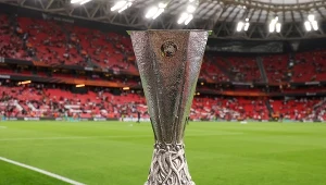 Puchar Ligi Europy UEFA ustawiony na stadionie przed rozpoczęciem meczu, w tle trybuny z kibicami i boisko piłkarskie.