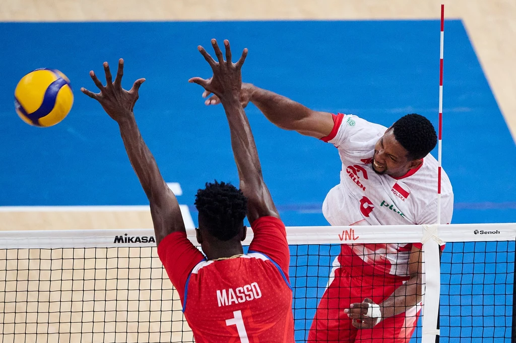 Mecz Polska - Kuba, w ataku Wilfredo Leon Dwóch siatkarzy walczy przy siatce o piłkę na hali sportowej, jeden z nich wykonuje atak, a drugi próbuje zablokować uderzenie unosząc ręce nad siatką.