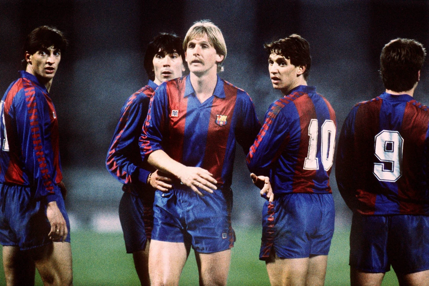 Bernd Schuster (trzeci od lewej) jest jednym z piłkarzy, którzy zamienili bezpośrednio FC Barcelona na Real Madryt. Potem do tego jeszcze grał on w... madryckim Atletico Grupa pięciu piłkarzy w niebiesko-bordowych strojach FC Barcelona, stojących blisko siebie na boisku podczas meczu, skoncentrowanych na sytuacji meczowej.