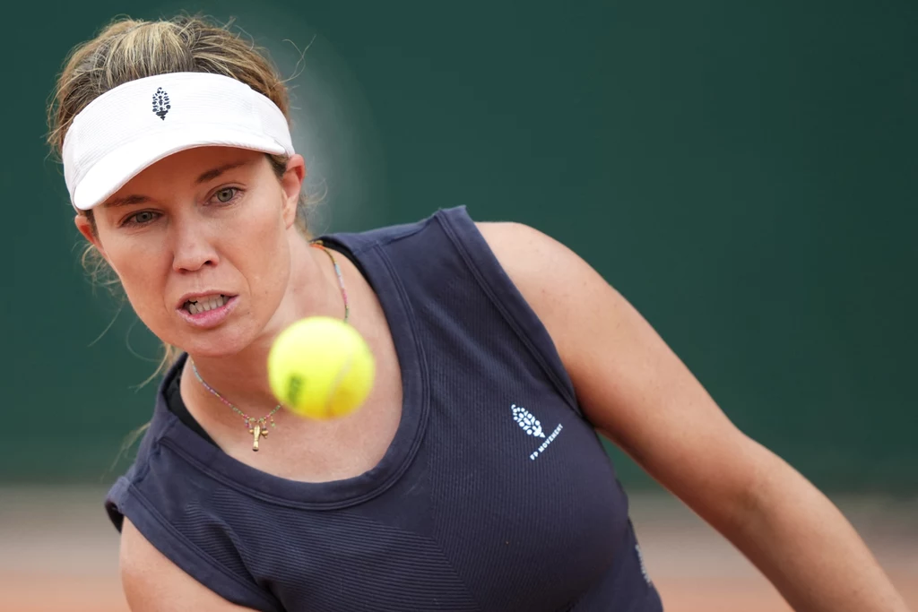 Danielle Collins Kobieta w sportowym stroju grająca w tenisa skupia się na lecącej w jej stronę żółtej piłce tenisowej, na tle zielonego boiska.