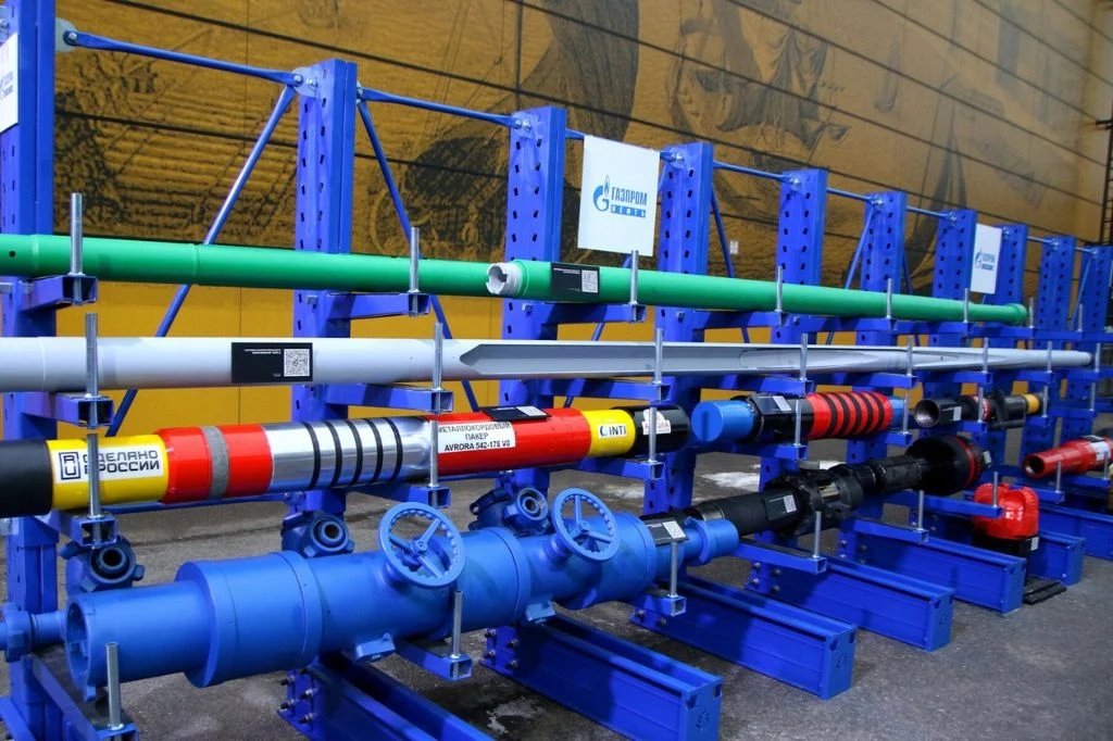 Ukraińcy dokonali cyberataku na rosyjskie przedsiębiorstwo Gazprom Rzędy różnokolorowych rur, zaworów i elementów instalacyjnych zamocowane na niebieskich stalowych stojakach, każda rura oznaczona etykietami oraz logotypami, całość ustawiona przy ścianie z dużą grafiką w tle.