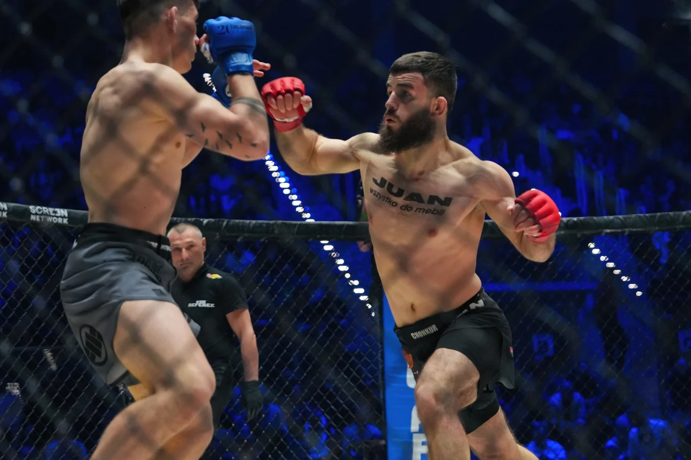 KSW: Adam Soldajew (z prawej) Dwóch zawodników walczy w klatce MMA podczas oficjalnej gali, jeden z nich wyprowadza mocny cios prawą ręką, widoczni są także sędzia i publiczność w tle.