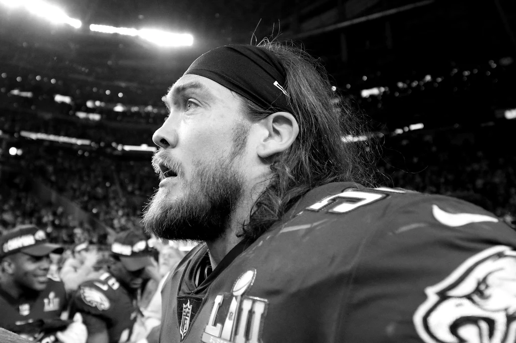 Bryan Braman Skoncentrowany zawodnik futbolu amerykańskiego w stroju drużyny z numerem 62 i logiem orła na ramieniu, w otoczeniu kibiców oraz stadionowych świateł