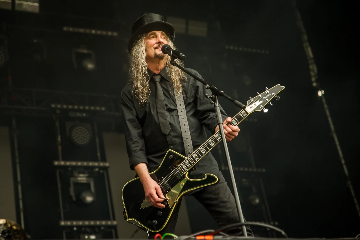 Hunter obchodzi w tym roku 40-lecie Mężczyzna z długimi, siwymi włosami i w czarnym kapeluszu gra na gitarze elektrycznej i śpiewa do mikrofonu na scenie koncertowej, ubrany na czarno, w tle oświetlenie sceniczne.