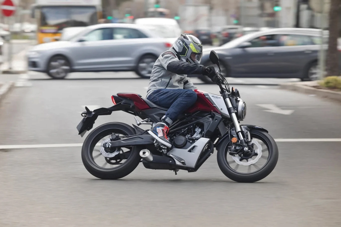 Mając prawo jazdy kategorii B można prowadzić nie tylko motocykle z silnikami o pojemności 125 cm3 Motocyklista w kasku przejeżdża przez miejską ulicę, w tle widać samochody i sygnalizację świetlną, a ruch uliczny sugeruje typowe warunki miejskie.