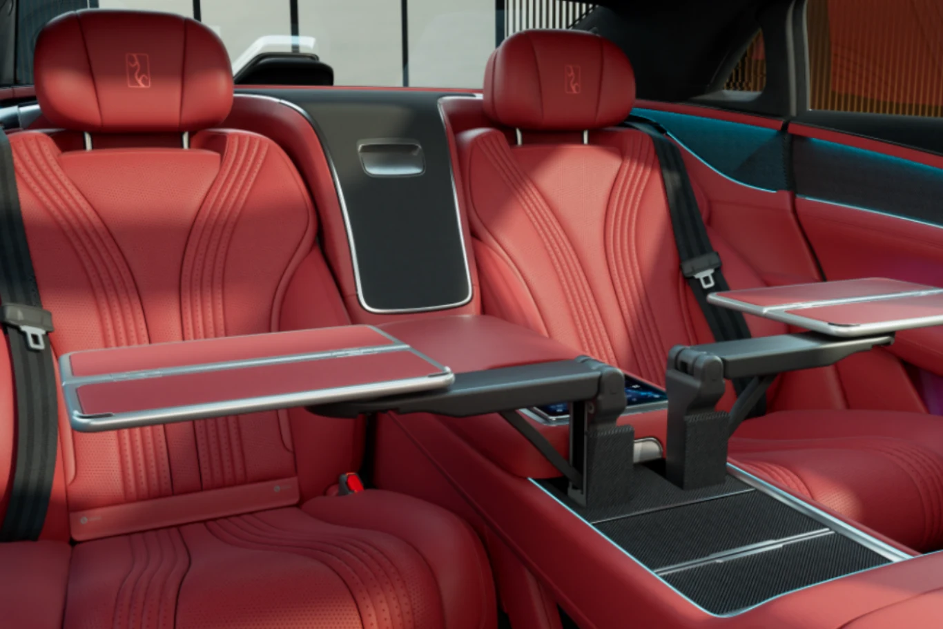 Luksusowe tylne siedzenia samochodu z czerwonej skóry, wyposażone w rozkładane stoliki oraz eleganckie przeszycia i detale. Wszystko utrzymane w nowoczesnym, ekskluzywnym stylu, podkreślającym wygodę i wysoką jakość wnętrza pojazdu.