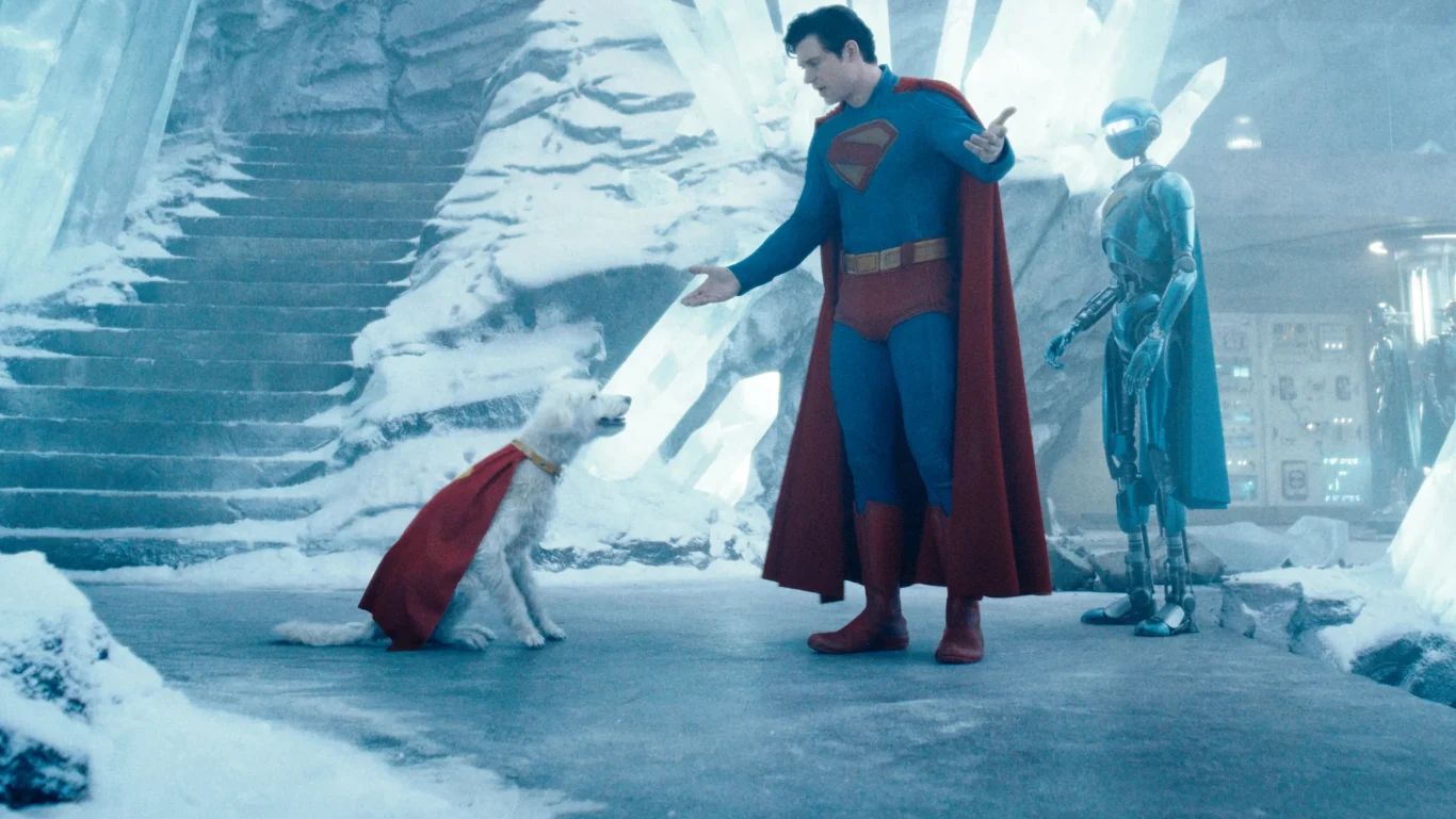 Pies Krypto z "Supermana" sprawił, że ludzie zaczęli interesować się adopcją zwierząt Mężczyzna w stroju superbohatera rozmawia z białym psem w czerwonej pelerynie, obok stoi robot, całość w futurystycznym, lodowym wnętrzu z kryształami.