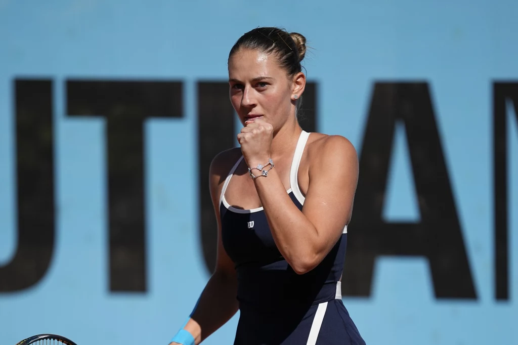 Marta Kostiuk skomentowała postawę Aryny Sabalenki Kobieta w sportowym stroju i spiętych włosach ściska dłoń w geście triumfu, znajdując się na zewnątrz na tle niebieskiej ściany z dużym napisem.