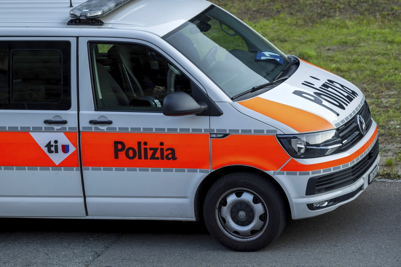 40-latek był więziony przez byłą partnerkę i przyjaciół Samochód policyjny z napisem 'Polizia' na drzwiach, biało-pomarańczowe barwy, widoczna sygnalizacja świetlna na dachu, pojazd stoi na jezdni przy trawiastym poboczu.