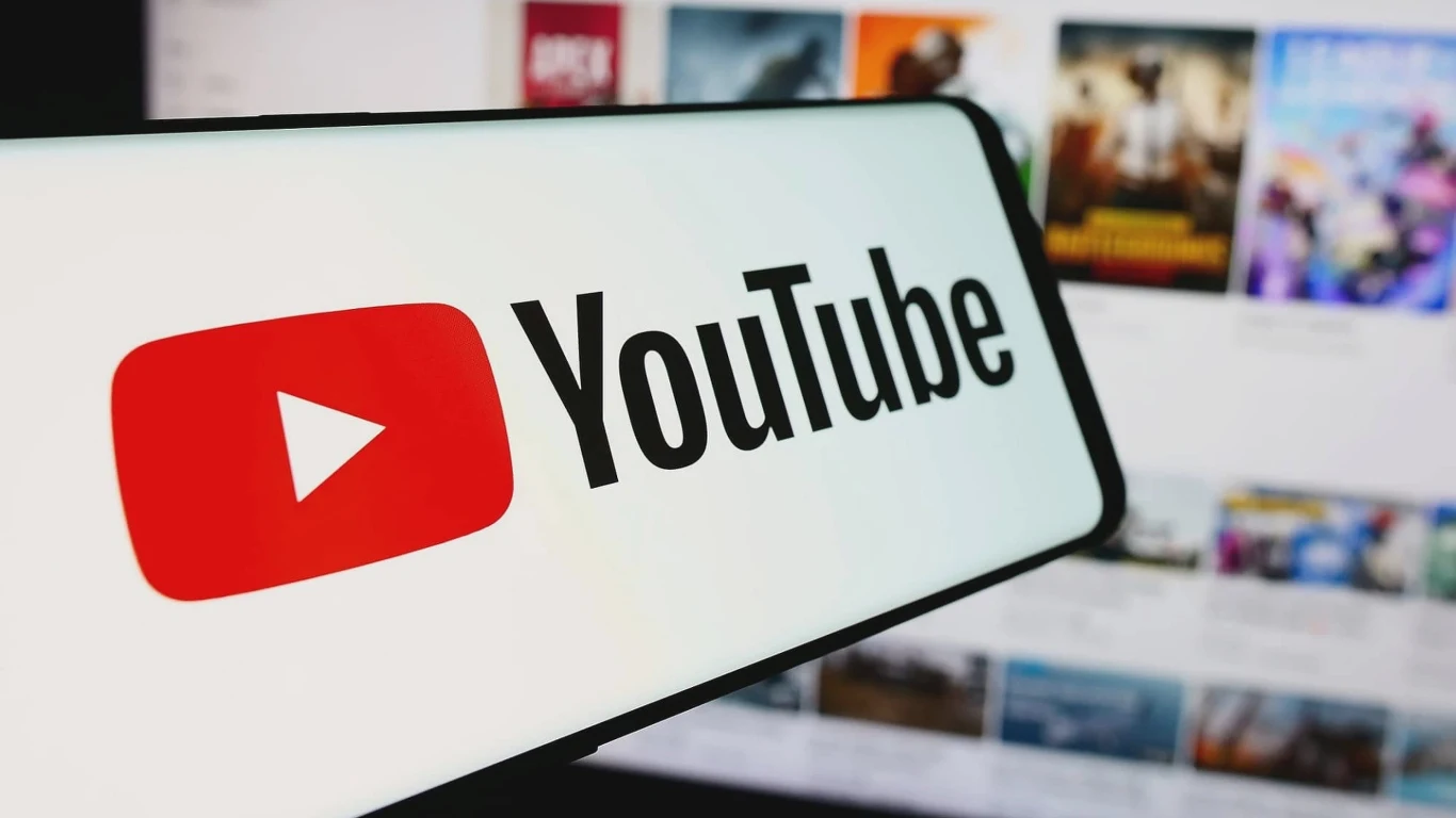 Wielkie czyszczenie na YouTube. Google usuwa tysiące kanałów Ekran telefonu z dużym, czytelnym logo YouTube na pierwszym planie, w tle rozmazane miniatury różnych filmów.