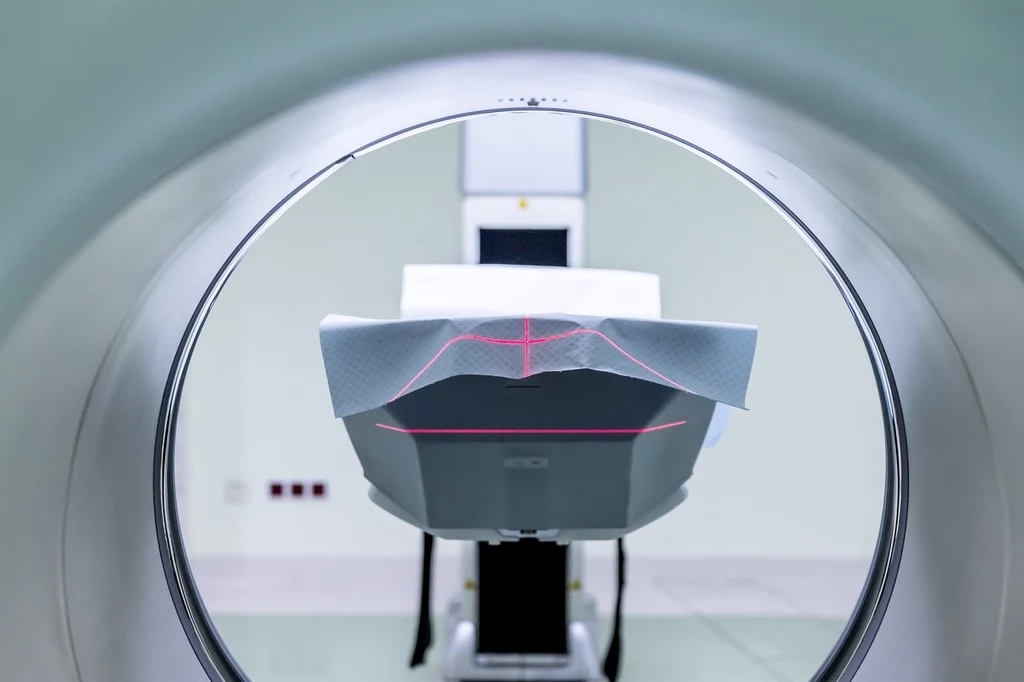 Przed rezonansem magnetycznym należy zdjąć wszelką biżuterię i metalowe przedmioty, które mogą zakłócać wyniki badania lub stanowić potencjalne zagrożenie dla pacjenta Wnętrze tunelu aparatu do rezonansu magnetycznego, na środku łóżko pacjenta z nakreślonymi czerwonymi liniami laserowymi służącymi do precyzyjnego ustawienia podczas badania.