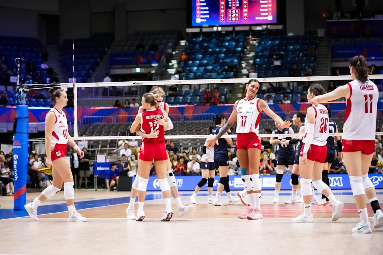 Polskie siatkarki, Aleksandra Szczygłowska w objęciach Julity Piaseckiej Grupa siatkarek w biało-czerwonych strojach świętuje punkt zdobyty podczas meczu na hali sportowej, w tle trybuny z kibicami oraz tablica wyników.