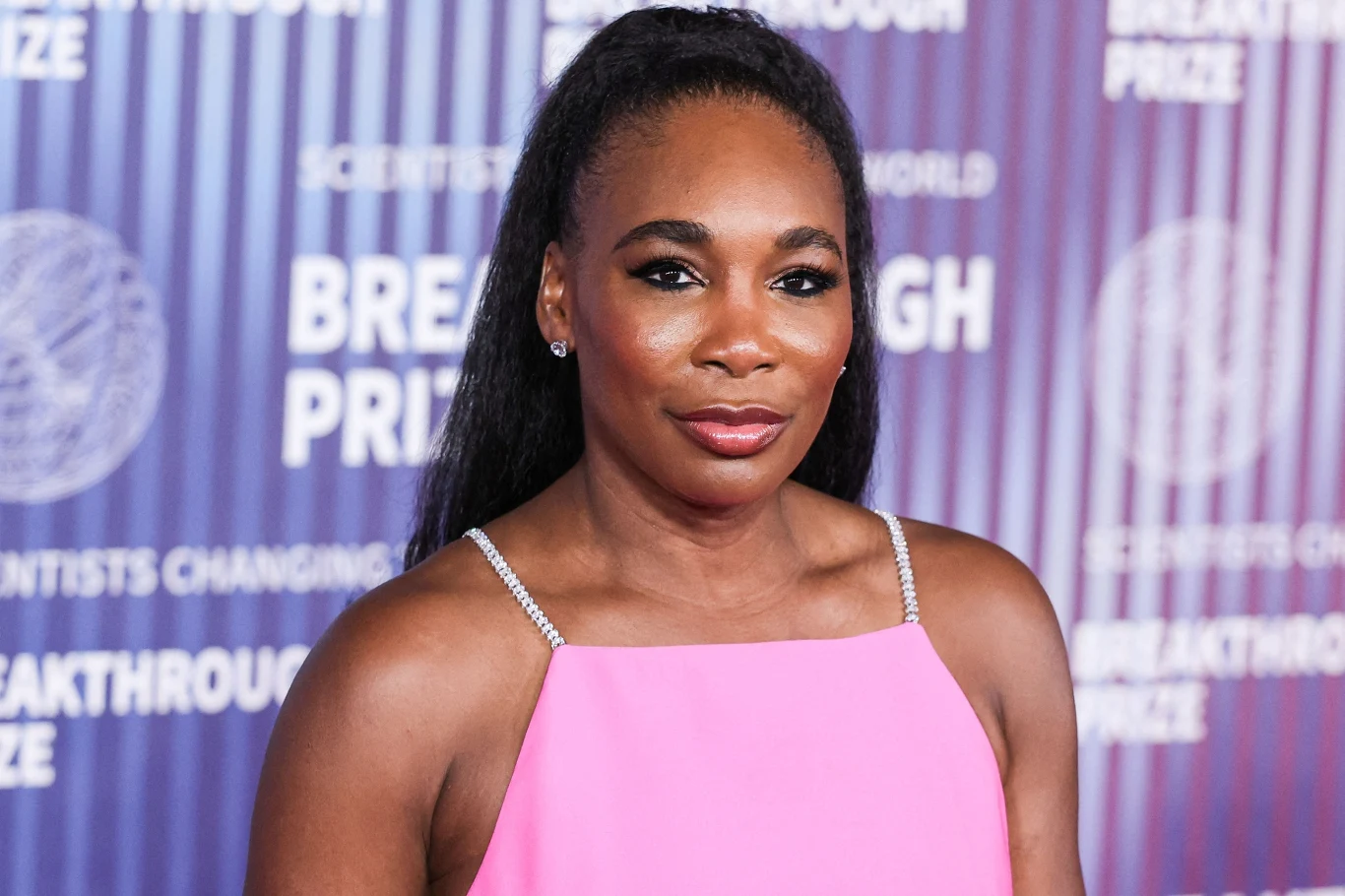 Venus Williams Kobieta w różowej sukni na tle ścianki z napisem Breakthrough Prize, elegancka stylizacja i fryzura spięta w koński ogon.
