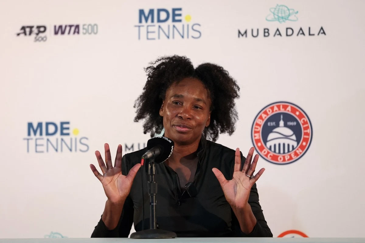 Venus Williams wróciła na kort. Już wiadomo, co ją motywowało Kobieta siedząca przy stole konferencyjnym z mikrofonem przed sobą, unosząca obie dłonie i uśmiechnięta, w tle logo turnieju tenisowego oraz partnerów wydarzenia.