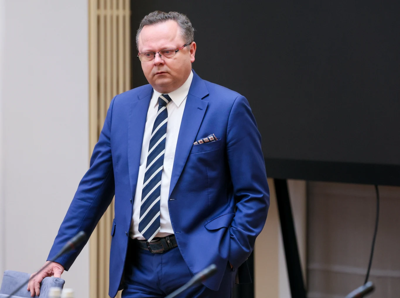Andrzej Szejna odchodzi z Ministerstwa Spraw Zagranicznych Mężczyzna w okularach ubrany w niebieski garnitur i biały krawat w paski stoi oparty o stół w jasnym pomieszczeniu, w tle widać czarny monitor.