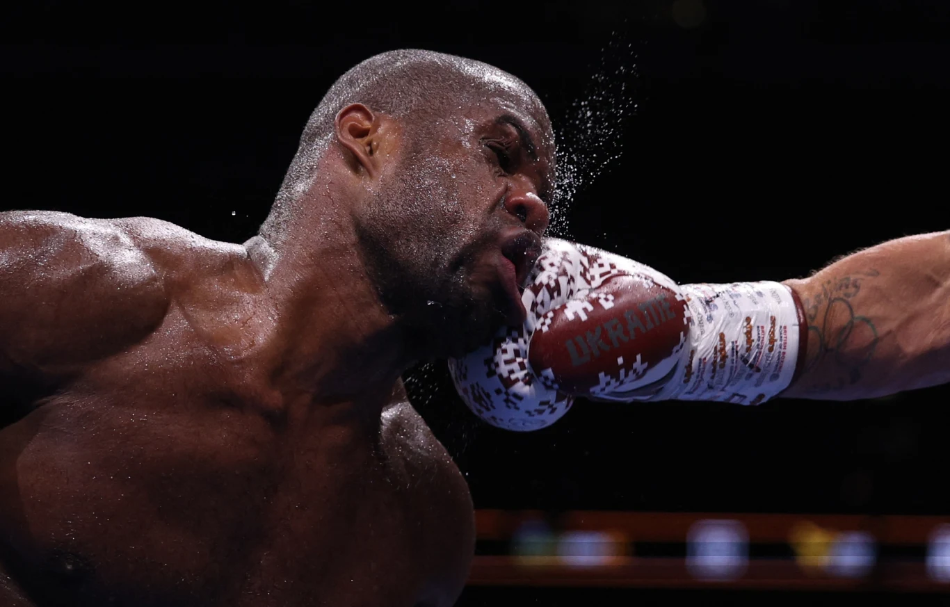 To ujęcie mówi wszystko. Ołeksandr Usyk potrafi wstrząsnąć nawet takimi gigantami, jak Daniel Dubois Bokser trafiany prawym prostym w twarz podczas walki, rozpryskujący się pot ukazuje siłę uderzenia, napięte mięśnie i skupienie.