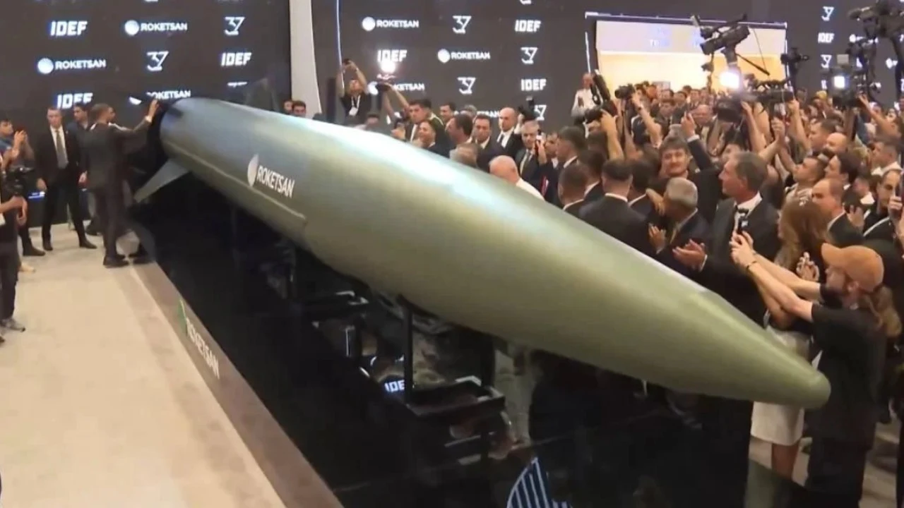 Nowy turecki pocisk Tayfun Block-4 Tłum osób w garniturach otacza dużą rakietę prezentowaną na targach technologicznych, wokół znajduje się wielu fotografów i stoisko promocyjne firmy Roketsan.