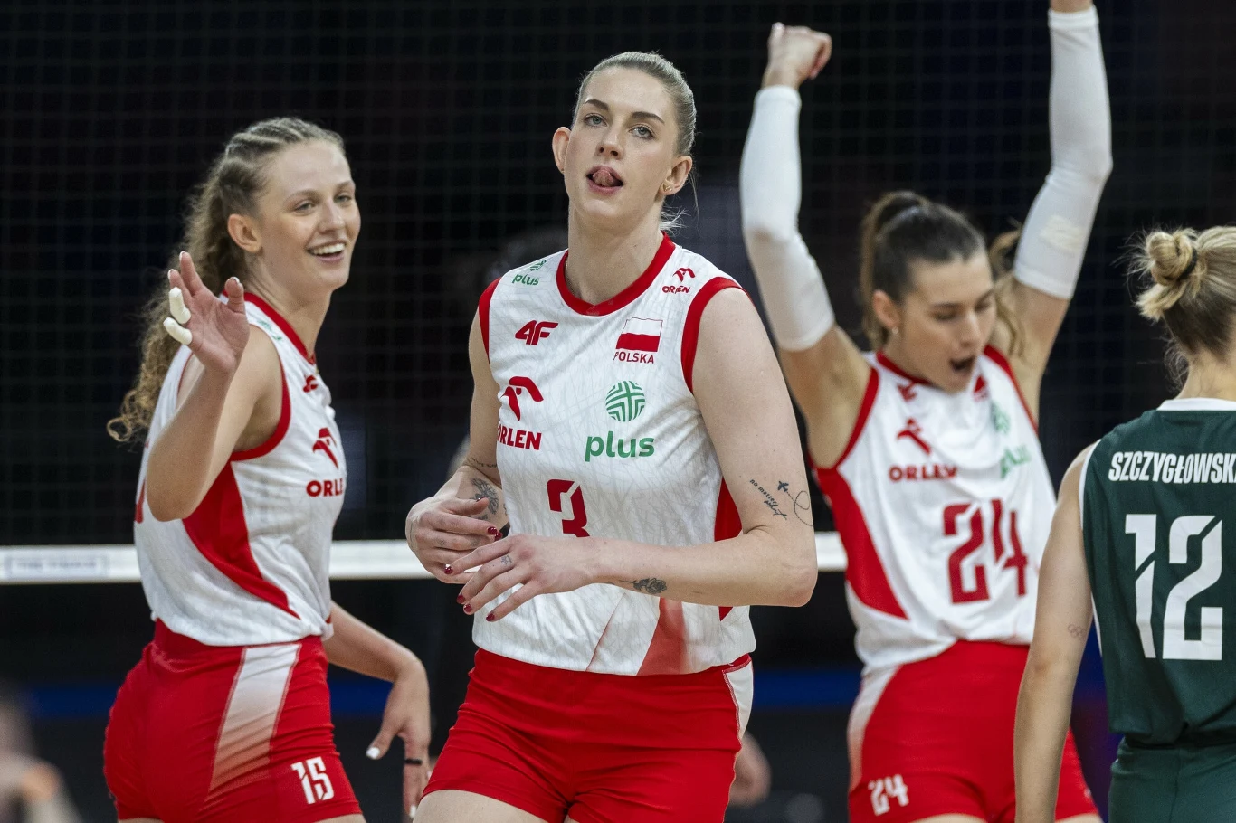 Zawodniczki polskiej reprezentacji siatkówki świętują zdobycie punktu podczas meczu, na pierwszym planie trzy uśmiechnięte siatkarki w czerwono-białych strojach z nazwiskami oraz numerami, w tle siatkarska siatka i rywalka w ciemnej koszulce.