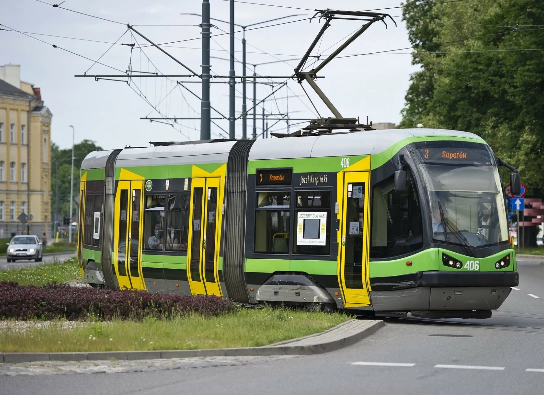 Tramwaj z lewej lub prawej? W tej sytuacji zasada jest jedna Nowoczesny zielono-żółty tramwaj poruszający się po zakręcie ulicy, otoczony infrastrukturą miejską i zielenią, w tle widoczne budynki mieszkalne oraz linie trakcyjne.