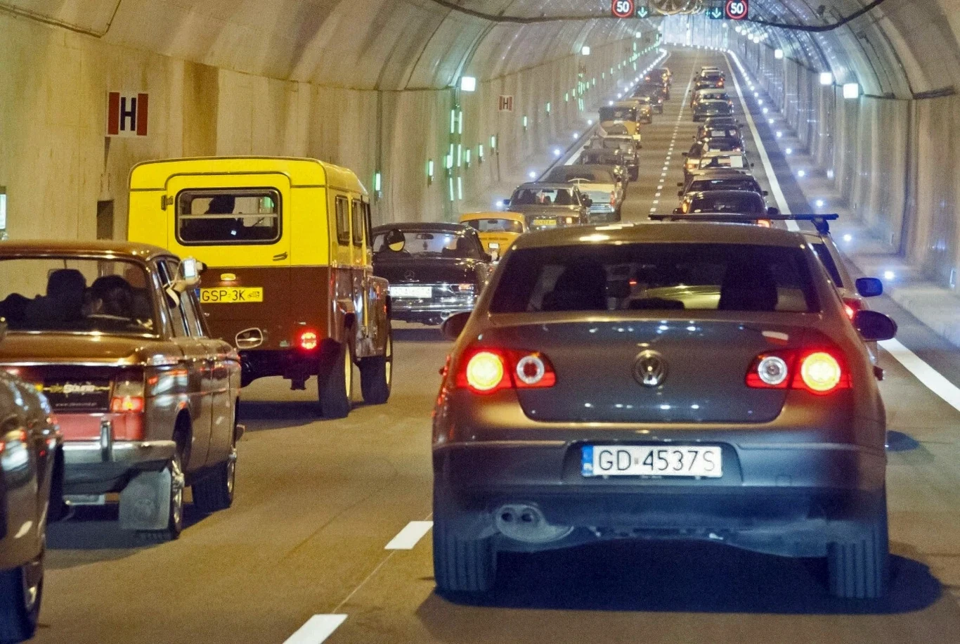 Tunel pod Martwą Wisłą zostanie zamknięty na czas prac serwisowych Korek samochodowy w tunelu, różnorodne pojazdy stojące na kilku pasach w sztucznie oświetlonym wnętrzu tunelu, widoczna rejestracja pojazdów, widok na perspektywę oddalającej się kolumny aut.