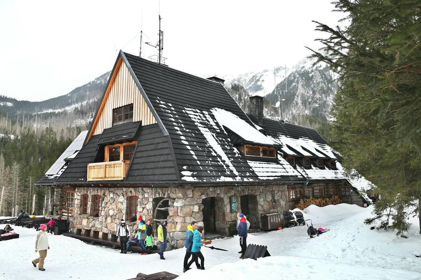 Schronisko PTTK na Hali Ornak to budynek utrzymany w stylu zakopiańskim lub, jak podkreślają niektóre źródła - nowozakopiańskim Kamienne górskie schronisko z czarnym, nachylonym dachem, częściowo pokrytym śniegiem, w otoczeniu lasu i zaśnieżonych szczytów. Przed budynkiem kilka osób w zimowych ubraniach szykuje się do wyjścia lub odpoczywa na tle zimowego krajobrazu.