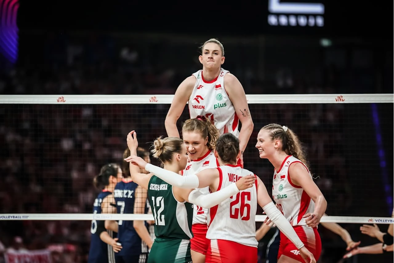 Martyna Czyrniańska (z prawej) i siatkarki reprezentacji Polski zagrają w półfinale Ligi Narodów Zawodniczki siatkarskiej reprezentacji Polski świętują zdobyty punkt podczas meczu, jedna z nich unosi się nad resztą zespołu na siatce, a reszta cieszy się razem, obejmując się.