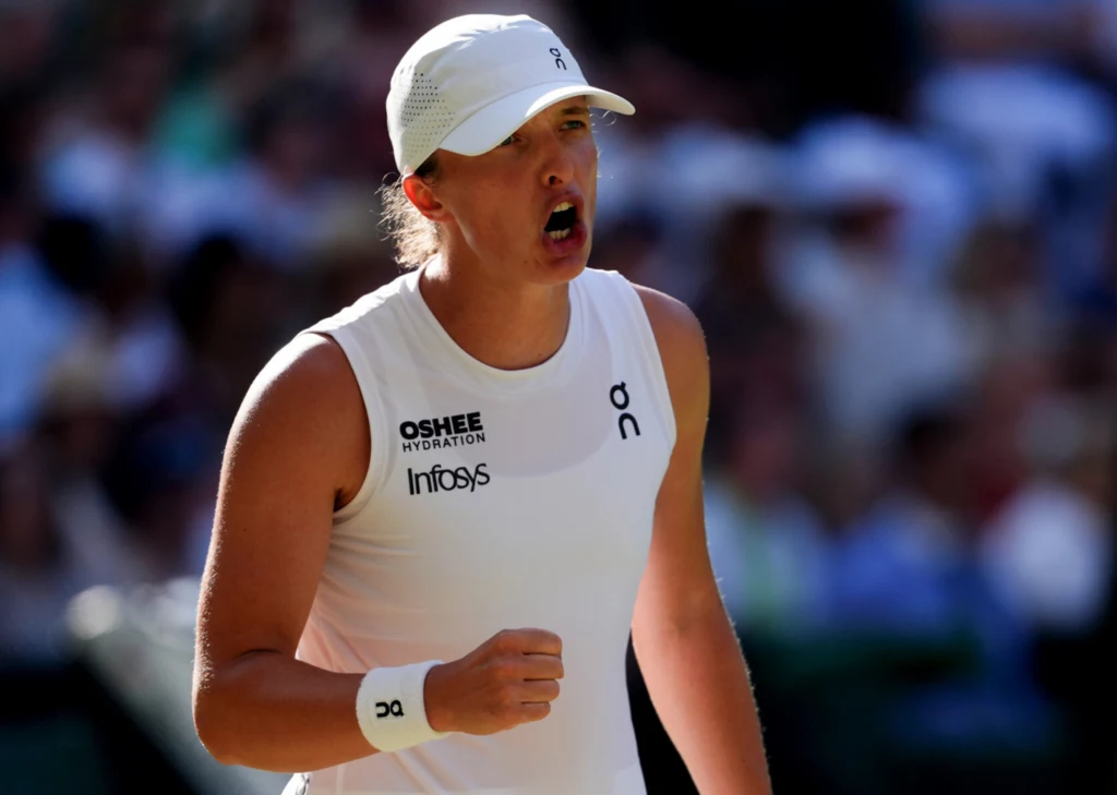 Iga Świątek - obecnie trzecia tenisistka rankingu WTA Sportowiec w białym stroju i czapce okazuje emocje w trakcie rywalizacji tenisowej, zaciska pięść i wydaje się wyrażać radość lub determinację po udanym zagraniu.