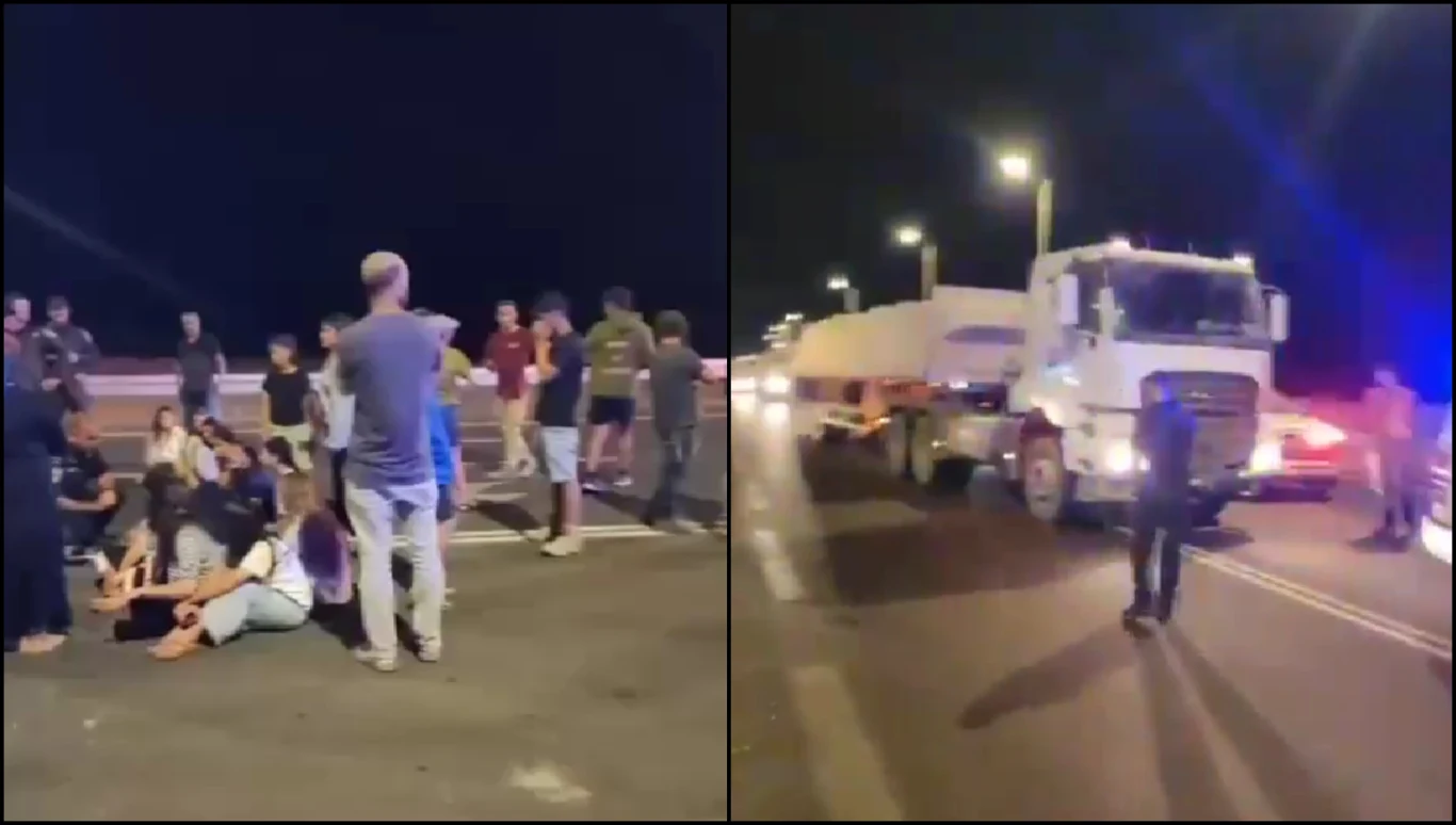 Palestyńskie media udostępniają nagranie, na którym widać blokadę przejazdu transportu pomocy humanitarnej Grupa ludzi siedzi i stoi na ulicy lub autostradzie w nocy, w tle widoczne ciężarówki i samochody, wokół światła uliczne oraz policja, sugerujące akcję protestacyjną lub blokadę drogi.