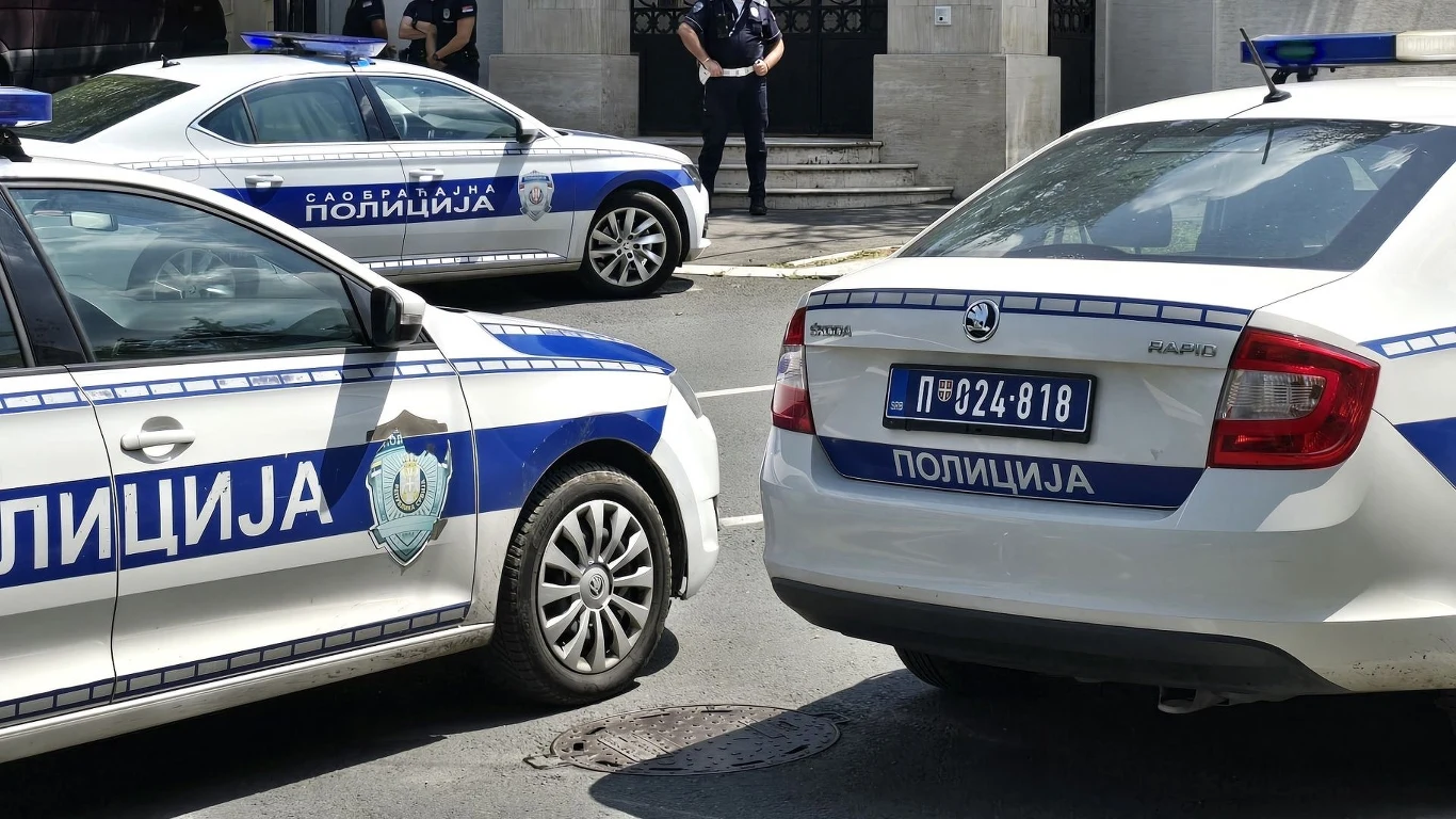 Atak na Polaka w Serbii (zdj. ilustracyjne) Radiowozy serbskiej policji zaparkowane na ulicy, w tle dwóch policjantów stojących przy budynku.