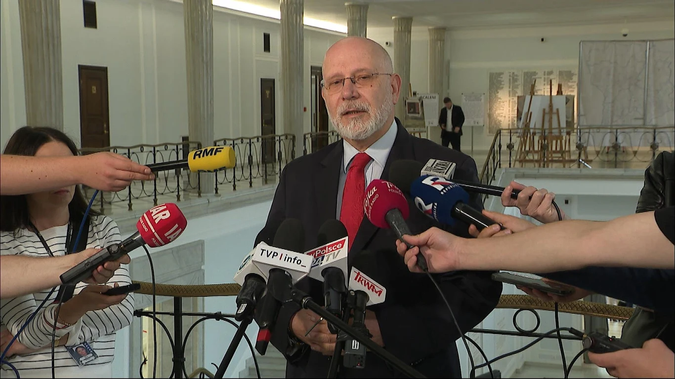 Sejm podjął decyzję w sprawie Macieja Świrskiego Mężczyzna w garniturze stoi przed licznymi mikrofonami różnych mediów, udzielając wypowiedzi lub wywiadu w przestronnym jasnym wnętrzu z widocznymi kolumnami i balustradą.