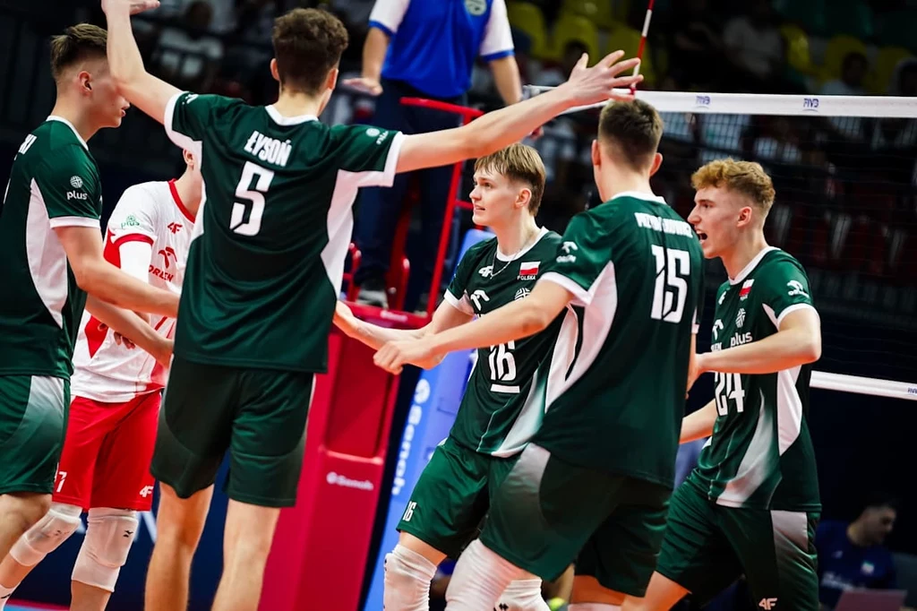 Siatkarska reprezentacja Polski U19 Grupa młodych siatkarzy w zielonych i białych strojach świętuje zdobycie punktu podczas meczu na hali sportowej, widoczne emocje i zaangażowanie zawodników.