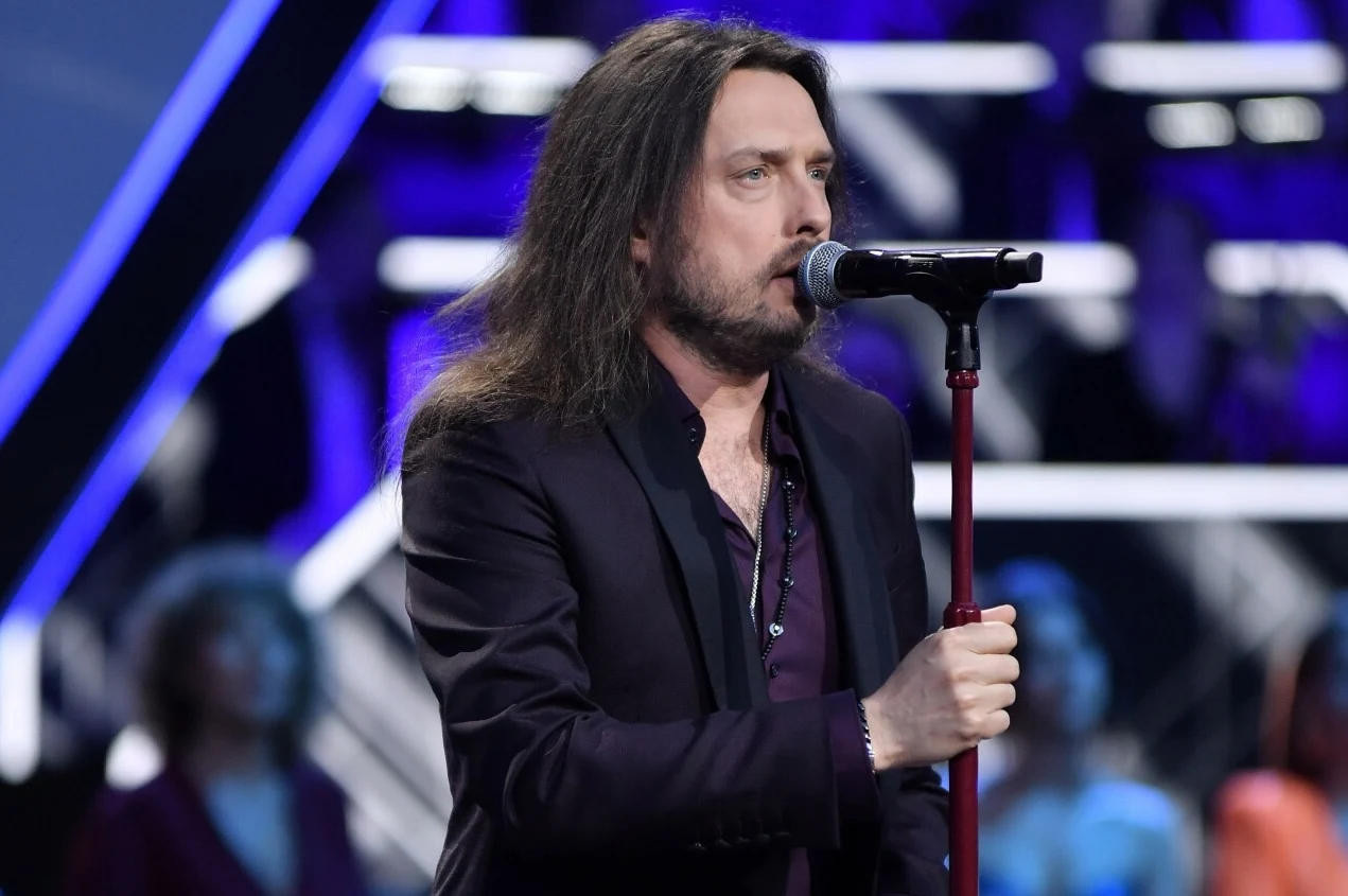 Piotr Cugowski zaśpiewał utwór Ozzy'ego Osbourna Mężczyzna z długimi włosami śpiewa do mikrofonu, ubrany w ciemną marynarkę, oświetlony reflektorami scenicznymi, w tle rozmyta publiczność i nowoczesna scenografia.