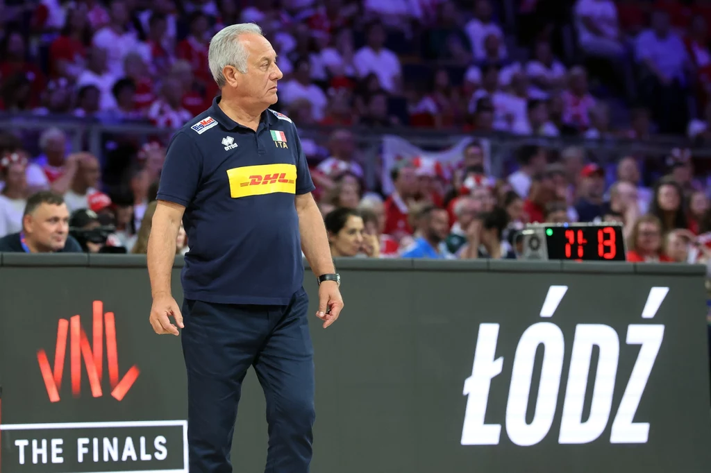 Julio Velasco Trener siatkówki w sportowym stroju stoi przy boisku podczas meczu finałowego, w tle widownia i widoczny napis Łódź oraz elektroniczny zegar.