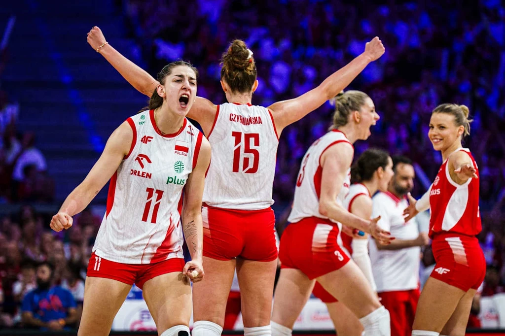 Zawodniczki drużyny siatkarskiej w biało-czerwonych strojach świętują zdobyty punkt na boisku, wyrażając radość i sportowe emocje, z widoczną energią oraz zadowoleniem.