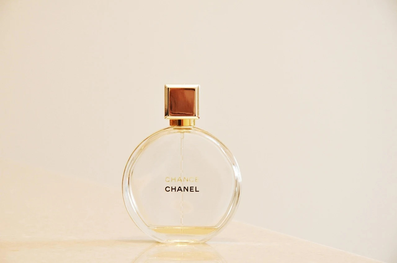 Perfumy renomowanych marek od lat kojarzą się z luksusem, klasą i… wysoką ceną Okrągły flakon perfum Chanel Chance z przezroczystego szkła, wypełniony jasnożółtym płynem, na jasnym tle z wyeksponowaną nazwą marki.