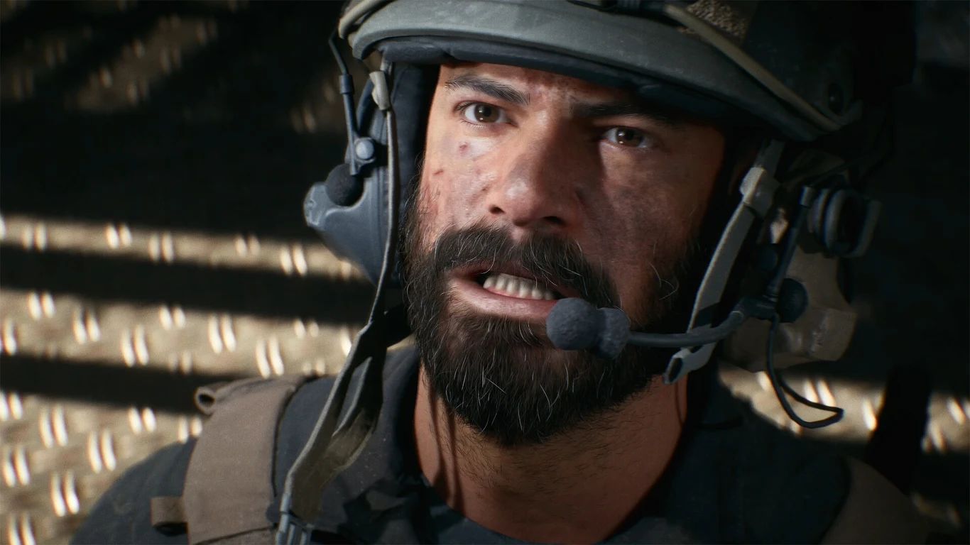 Battlefield 6 Mężczyzna z brodą i hełmem wojskowym z mikrofonem na głowie, ubrany w kamizelkę taktyczną, patrzący z powagą w stronę kamery, na twarzy widoczne ślady zabrudzeń i stresu.