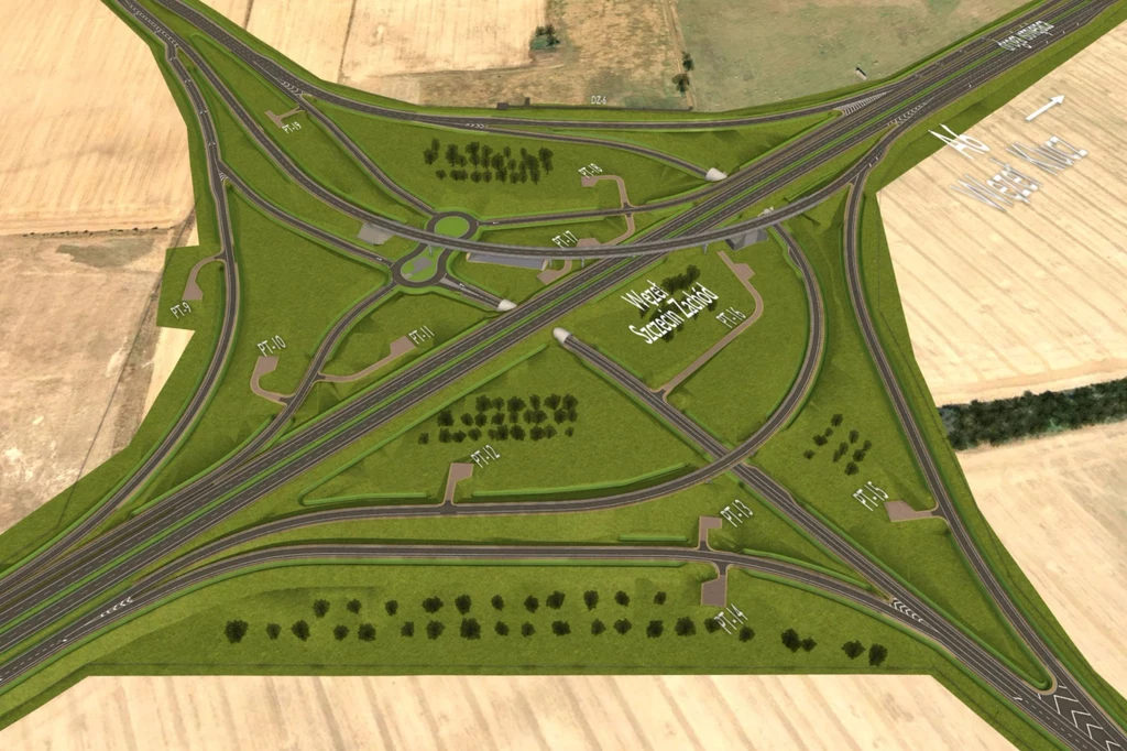 skrzyżowanie dwóch autostrad tworzące rozbudowany węzeł komunikacyjny na tle pól uprawnych, wyraźnie widoczne zjazdy, ronda, oznakowane drogi serwisowe oraz zorganizowana zieleń w postaci drzew i trawników