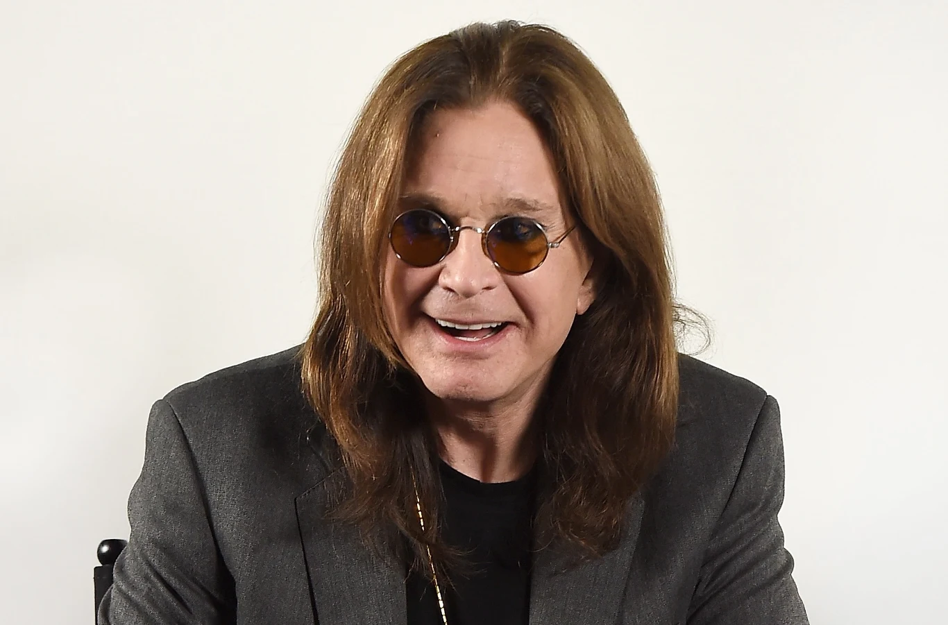 Ozzy Osbourne miał bardzo dobre zdanie o Taylor Swift Mężczyzna z długimi, brązowymi włosami w ciemnych okularach przeciwsłonecznych, ubrany w ciemną marynarkę, uśmiecha się patrząc lekko na bok na jasnym tle.