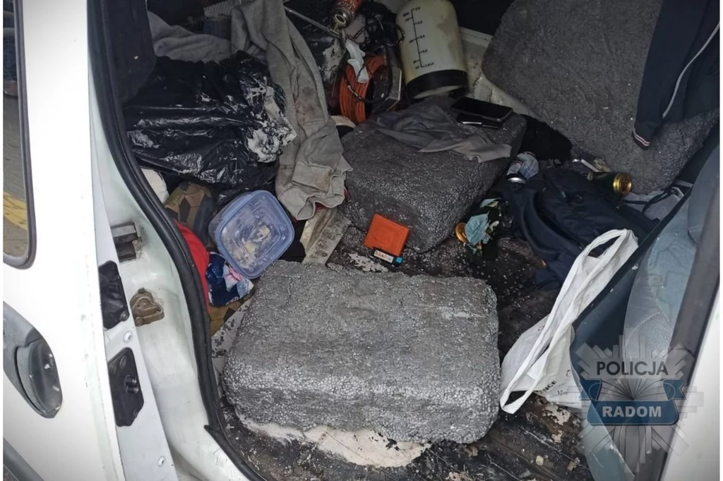 Wnętrze samochodu wypełnione różnymi przedmiotami, w tym betonowe prostopadłościany, torby, pojemniki, ubrania oraz narzędzia. W rogu widoczny napis 'Policja Radom' sugerujący udział służb w obecnej sytuacji.