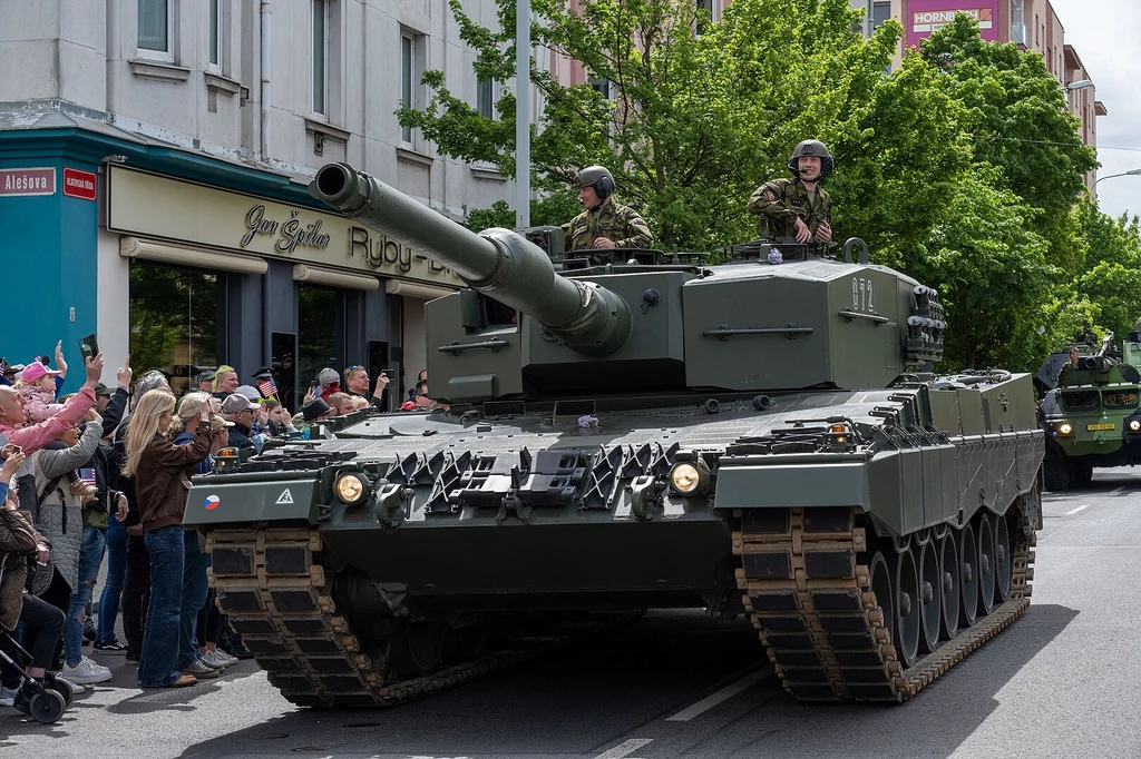 Pierwszy Leopard 2A4 trafił do rąk Czechów w grudniu 2022 Czołg wojskowy typu Leopard jedzie ulicą miasta, wokół niego zgromadzony tłum ludzi obserwujący wydarzenie, część z nich robi zdjęcia, na czołgu widoczni są umundurowani żołnierze.