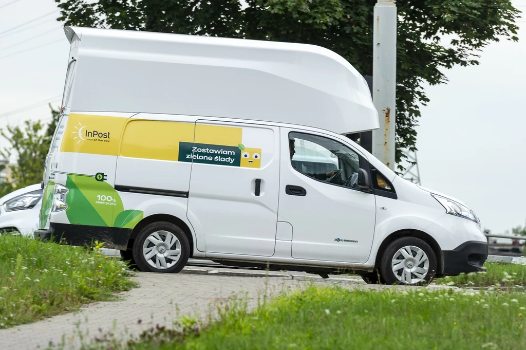 Zarzuty UOKiK dotyczą m.in. "zielonego" przekazu marketingowego firm kurierskich Samochód dostawczy firmy InPost z widocznym logo oraz hasłem reklamowym na boku pojazdu, zaparkowany na chodniku w pobliżu ulicy, w tle drzewa oraz fragment innego samochodu.