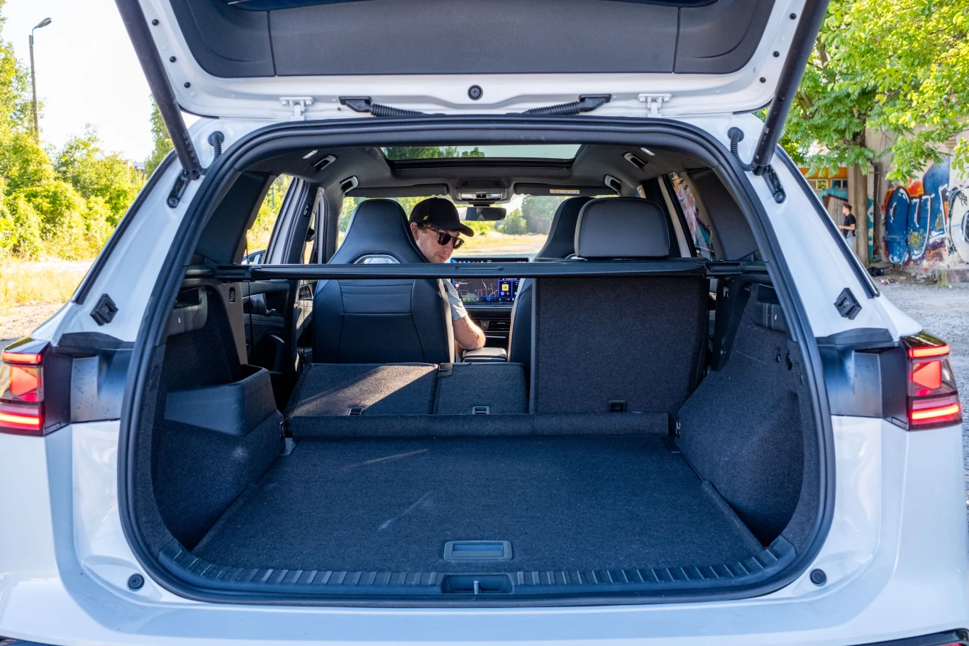 Bagażnik jest przepastny i ma podłogę o regulowanej wysokości, jednak po złożeniu kanapy powierzchnia nie jest równa. Widok z otwartego bagażnika samochodu typu SUV z rozłożonymi tylnymi siedzeniami, na miejscu kierowcy siedzi mężczyzna w okularach przeciwsłonecznych.