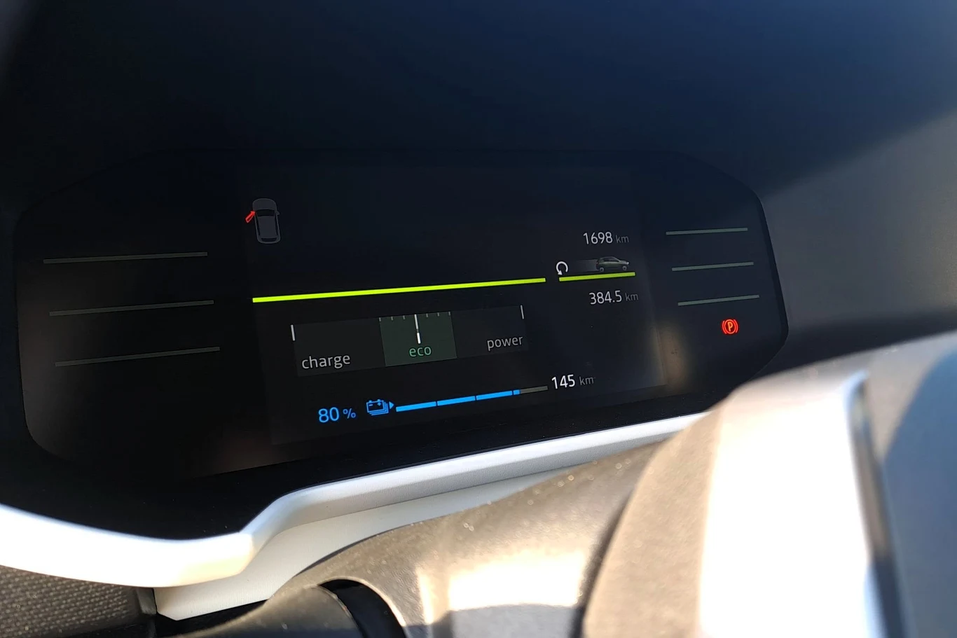 Cyfrowy panel wskaźników pojazdu elektrycznego z widocznym poziomem naładowania baterii wynoszącym 80%, informacją o pozostałym zasięgu 145 km oraz wskaźnikiem trybu jazdy eco.