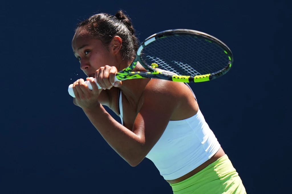 Leylah Fernandez Tenisistka w sportowym stroju skupiona na wykonywaniu zamachu rakietą tenisową na tle niebieskiego boiska.