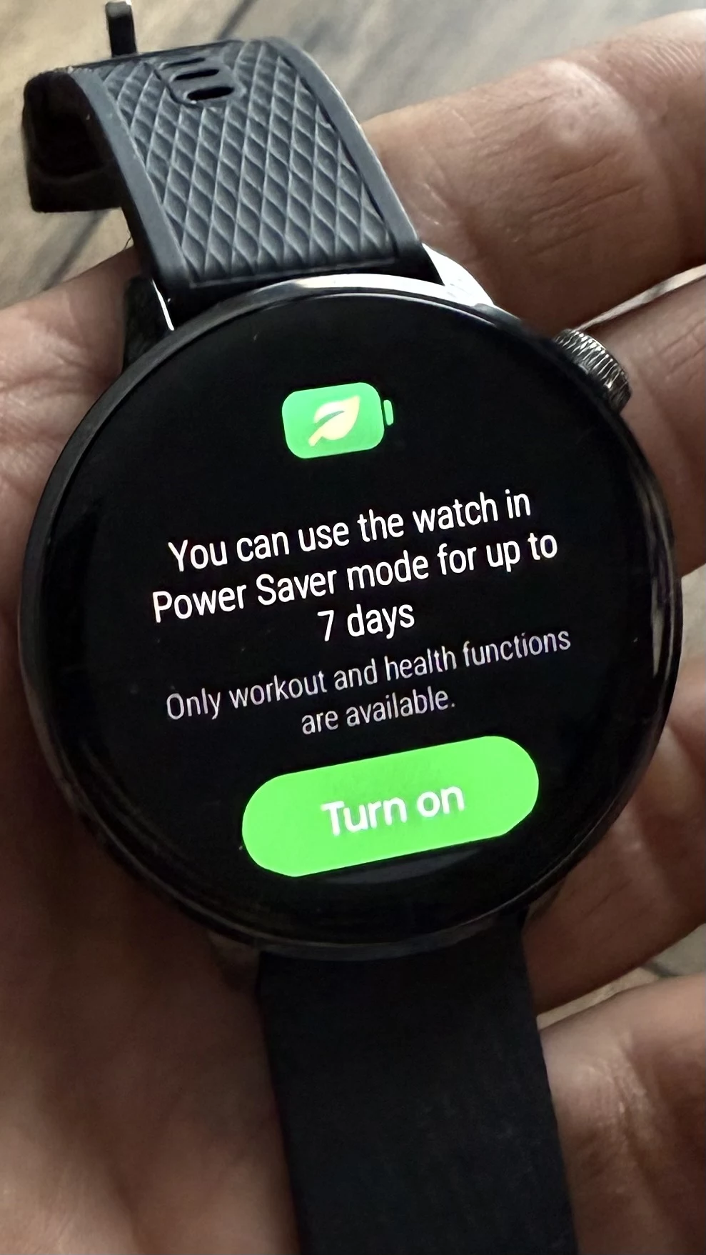 OnePlus Watch 3 43 mm ma specjalny tryb, który wydłuża czas pracy do 7 dni, ale to powoduje wyłączenie części funkcji. Nowoczesny zegarek typu smartwatch trzymany w dłoni, na wyświetlaczu komunikat o możliwości korzystania z trybu oszczędzania energii do 7 dni, z dostępem tylko do funkcji treningowych i zdrowotnych.